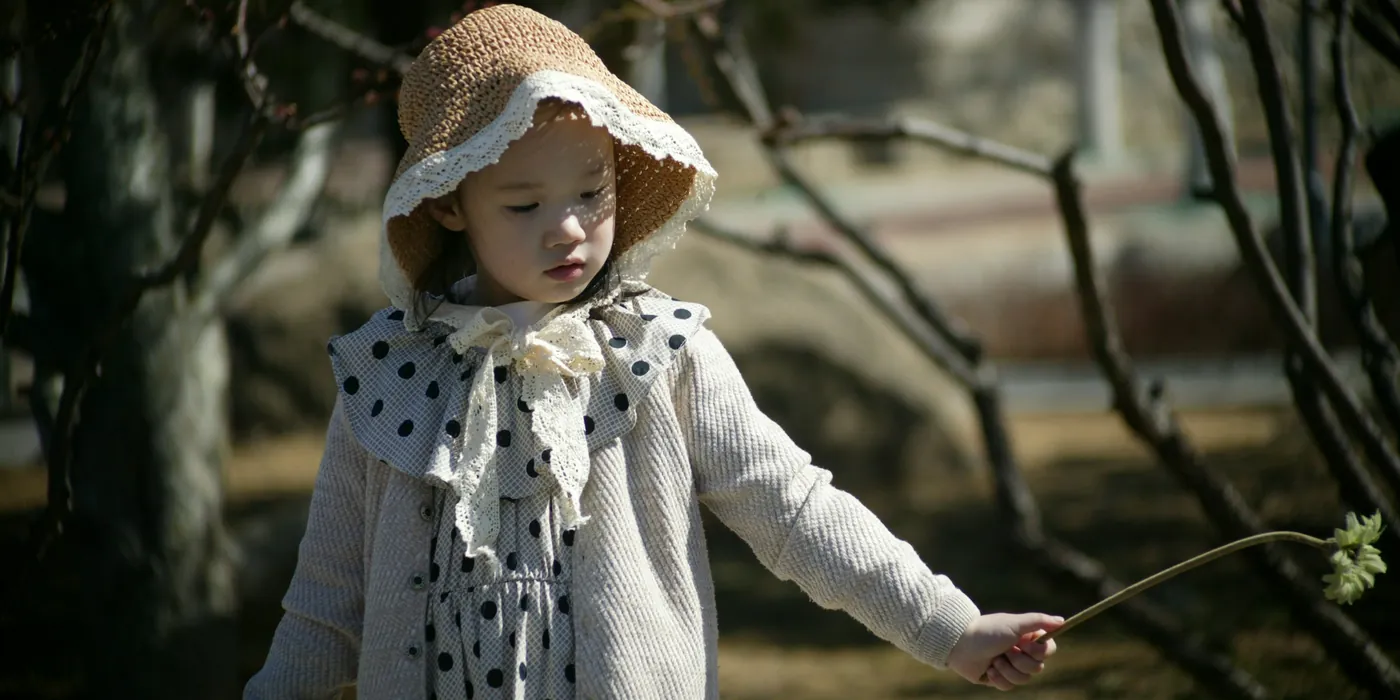 Girl in a crochet bonnet, cardigan and polka dot dress exploring the woods