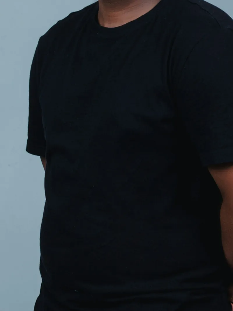 Model in a black heavyweight crew t-shirt against a blue-grey backdrop